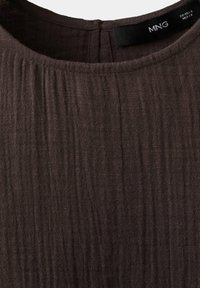 Haut en tissu texturé marron foncé avec col rond et étiquette de marque visible "MNG" au niveau du col derrière.