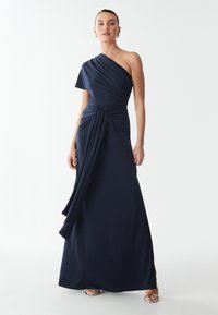 Abito navy blue monospalla con corpino drappeggiato e dettaglio di nodo laterale. Realizzato in tessuto morbido, presenta una gonna fluente e uno spacco laterale.