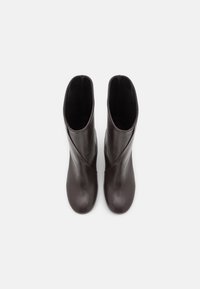 Bruna läderankelboots med en slät yta, med rund tå och en asymmetrisk design vid skaftet.
