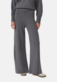 Gray wide-leg knit pants worn with matching gray sweater and white sneakers, shown on a standing person against a neutral background.