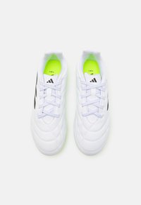 Zapatillas deportivas blancas con un diseño acolchado, acentos negros y plantillas verdes claras. Cuentan con cordones blancos y una forma de puntera redondeada.