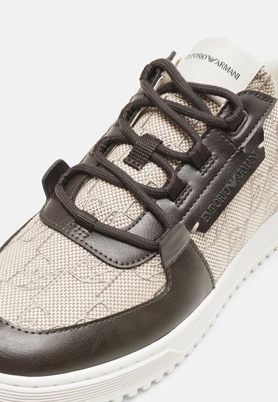 Baskets Emporio Armani beige clair et marron foncé avec tissu texturé, accents en cuir, lacets noirs et semelle blanche.