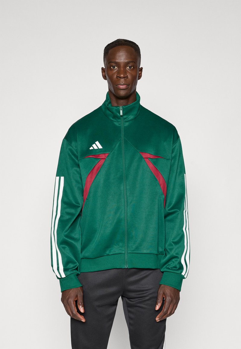Groene sportjack met hoge kraag, voorzien van bordeauxrode accenten en een wit driedelig ontwerp op de mouwen. Gemaakt van soepel, lichtgewicht materiaal.