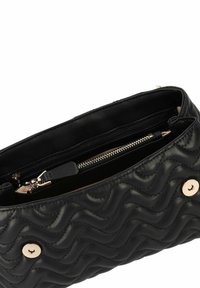 Bolso de mano acolchado negro hecho de cuero, con un patrón de olas texturizado, bolsillo con cremallera y acentos de hardware en tono dorado.