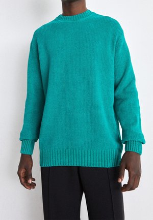 Türkiser Strickpullover mit rundem Ausschnitt, gerippten Ärmelbündchen und Saum. Hergestellt aus strukturiertem Stoff, mit langen Ärmeln und oversize Passform.