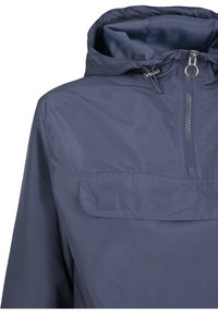 Marineblauwe lichtgewicht windjack met een rits aan de voorkant, een trekkoordkap en een grote voorkantzak, gemaakt van glad, waterafstotend materiaal.