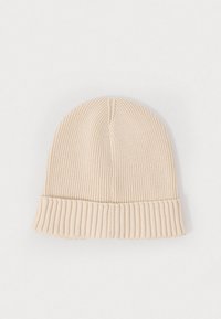 Bonnet en tricot de couleur beige clair, avec un bord côtelé et une texture lisse. Dessus rond avec des détails de couture verticale, conçu pour la chaleur.