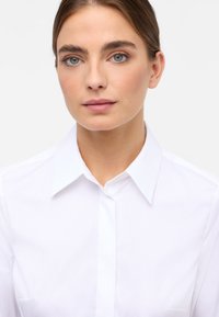 Witte overhemden met een klassieke kraag, van gladde katoenstof en met lange mouwen. Bevat een verborgen knoopsluiting aan de voorkant en een borstzak aan de linkerzijde.