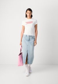 Hvit t-skjorte med rødt "tommy jeans"-logo, lyseblå denimskjørt med frontsplitt, rosa totebag, hvite sneakers, og hvite sokker.
