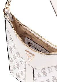 Sac à épaule en cuir blanc avec quincaillerie dorée, un poche zippée intérieure et une doublure à motif avec un design de logo.