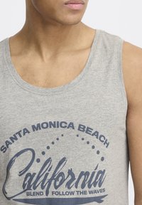 Top de tirantes de algodón gris con cuello redondeado y un estampado que dice "Santa Monica Beach California Blend Follow the Waves" en color azul oscuro.