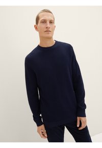 Marineblaues Strickpullover mit Rundhalsausschnitt, langen Ärmeln und gerippten Bündchen. Verfügt über ein strukturiertes Muster auf dem gesamten Stoff.