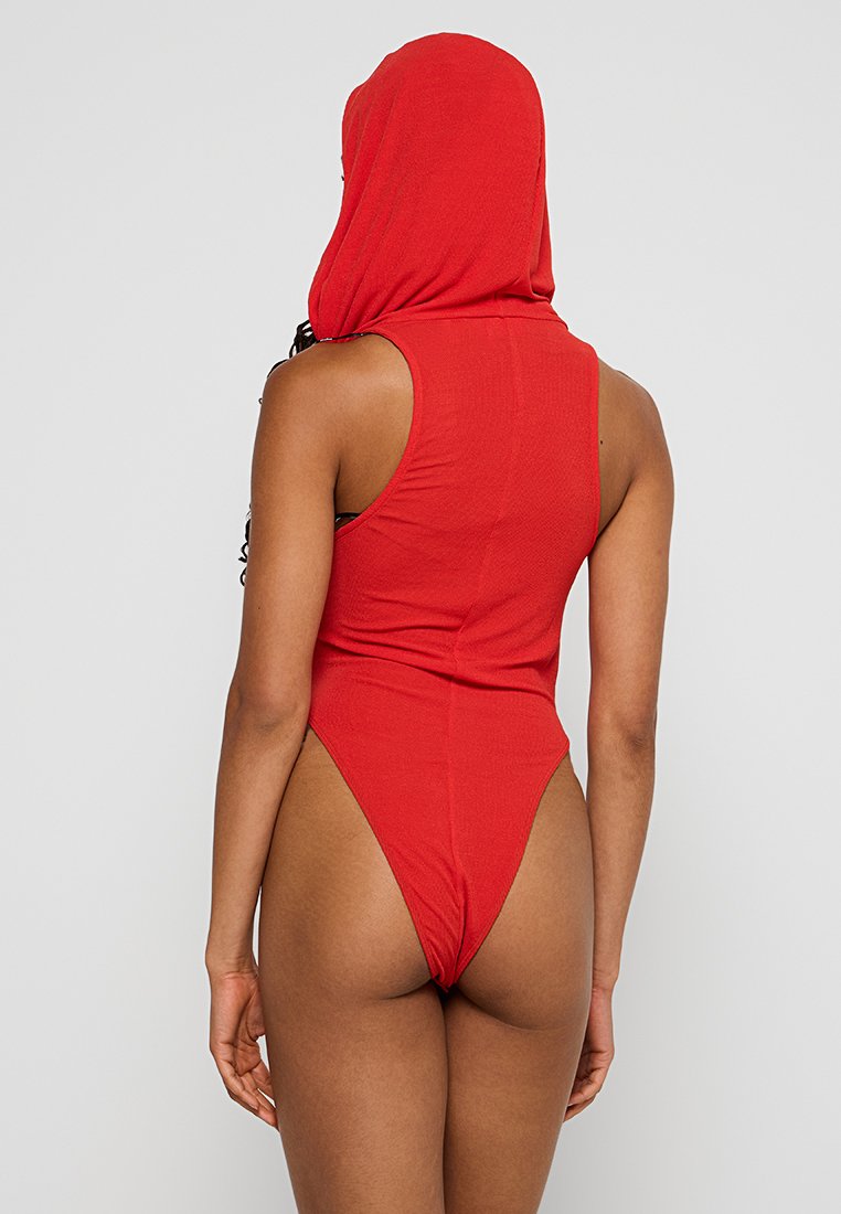 Czerwony jednoczęściowy strój kąpielowy z kapturem, cechujący się wysokim wycięciem nogawki i prążkowaną teksturą. Widok z tyłu podkreśla dopasowany kształt i minimalne krycie.
