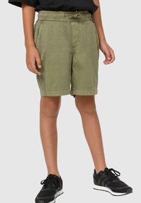 Shorts vert olive avec une taille élastique et un cordon de serrage, dotés de poches latérales et d'une coupe décontractée, associés à des chaussures de sport noires.
