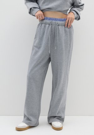 Graue Jogginghose mit einem elastischen Bund, der innen blau-weiß gestreift ist. Sie hat eine lockere Passform und einen verstellbaren Kordelzug.