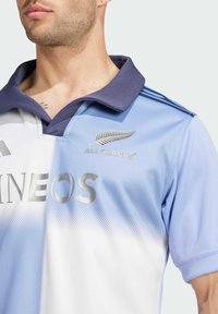 Vaaleansininen ja valkoinen rugby-paita, jossa tummansininen kaulus. Paidassa on hopeinen "INEOS"-teksti ja "All Blacks" -logo rinnassa.