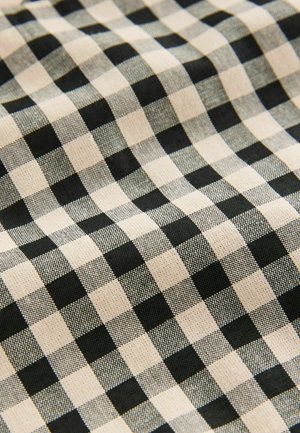Tissu à carreaux noir et beige présentant un motif en grille avec des carrés alternés, fait d'un matériau texturé.