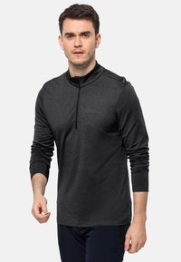 Schwarzer Pullover mit langen Ärmeln und halbem Reißverschluss-Kragen. Hergestellt aus strukturiertem Stoff, mit einem dezenten Logo auf der Brust und eng anliegenden Ärmeln.