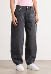 Black wide-leg jeans with a high waist, featuring five pockets, metal button, and contrasting stitching. Fabric appears denim texture.