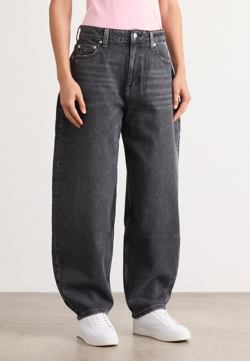 Black wide-leg jeans with a high waist, featuring five pockets, metal button, and contrasting stitching. Fabric appears denim texture.