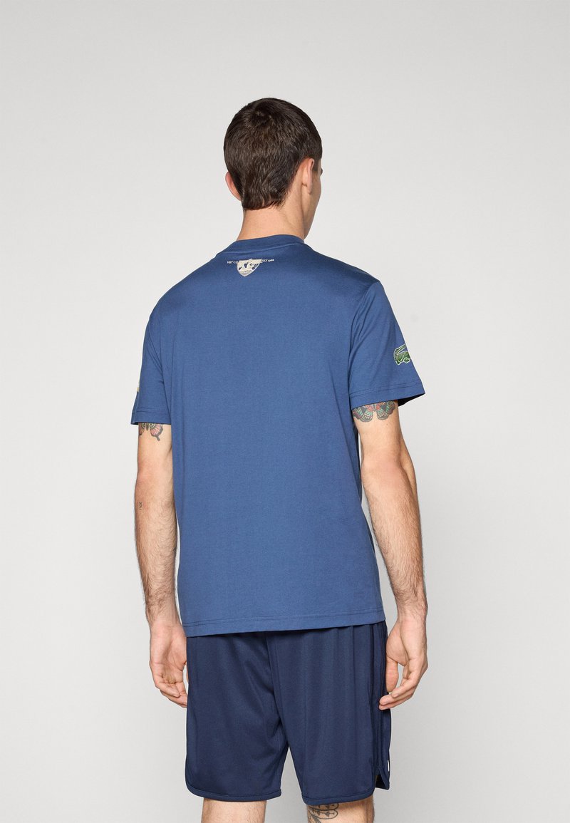 T-shirt en coton bleu marine à manches courtes, encolure ronde et étiquette logo dans le dos. Porté avec un short bleu marine assorti.