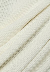 Off-White gestrickter Stoff mit einem strukturierten Muster aus erhabenen Punkten und horizontalen Streifen. Weiches, leichtes und atmungsaktives Material.