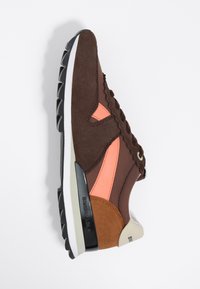 Brązowy zamszowy sneaker z pomarańczowymi i brązowymi akcentami, z wiązaniem na sznurówki, teksturowanymi panelami oraz czarną gumową podeszwą z białą krawędzią.