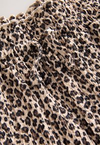 Béžová látka s černým a hnědým leopardím vzorem, s nařasenou gumou a zavazovacím stahovacím páskem.