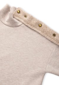 Beżowy pulower z półgolfem, z teksturowaną filcową wstawką na ramieniu ozdobioną złotymi guzikami. Miękka tkanina o gładkim wykończeniu.