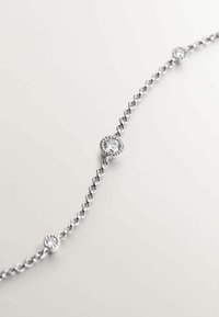 Pulsera de cadena de plata con tres acentos circulares de diamantes espaciados de manera uniforme, con un acabado pulido y brillante y un diseño delicado.