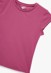 T-shirt à manches courtes en tissu uni rose foncé. Il présente un col rond et une texture lisse avec des coutures nettes le long de l'ourlet et des manches.