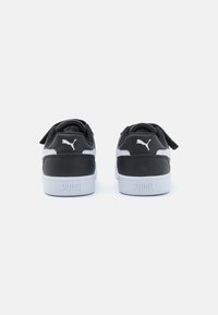 Baskets noires et grises avec un dos rembourré, présentant des accents blancs et un logo. La semelle est blanche avec des motifs texturés pour l'adhérence.