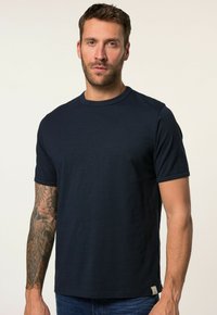 Námorně modré tričko s kulatým výstřihem vyrobené z měkké tkaniny, s krátkými rukávy a decentní značkovou visačkou na spodní části.