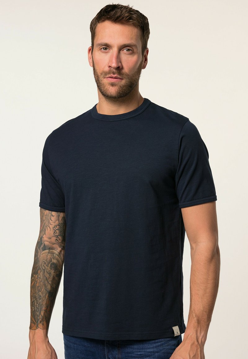 Námorně modré tričko s kulatým výstřihem vyrobené z měkké tkaniny, s krátkými rukávy a decentní značkovou visačkou na spodní části.