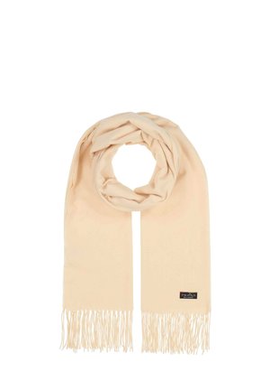 Écharpe beige en tissu doux, présentant des franges aux extrémités et une texture subtile, avec une étiquette de marque attachée sur un côté.