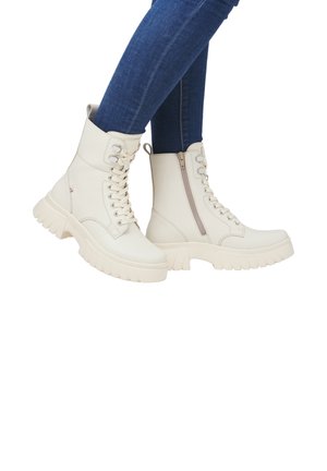 White ankle boots with a chunky, textured sole, featuring laces and a side zipper for easy access. Smooth leather material with a minimalist design.