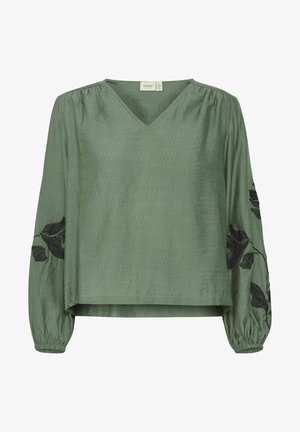 Roheline, tekstuuriga pluus V-kaeluse ja pikkade varrukatega. Musta tikandiga lehe ornamentika varrukatel, elastsed mansetid, lõdva istuvusega.