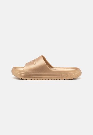 Gullfarget slip-on sandaler med en jevn tekstur, med en bred stropp og en rillet såle. Merkevaren sin logo er preget på siden.