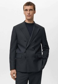 Blazer de doble botonadura en gris oscuro con solapas de pico, dos bolsillos delanteros y botones negros. Tejido liso con un ajuste entallado.