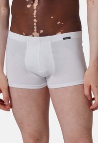 Boxer da uomo in cotone bianco con design aderente, vita elastica e una piccola etichetta del marchio sulla vita. Tessuto liscio e senza fantasie.