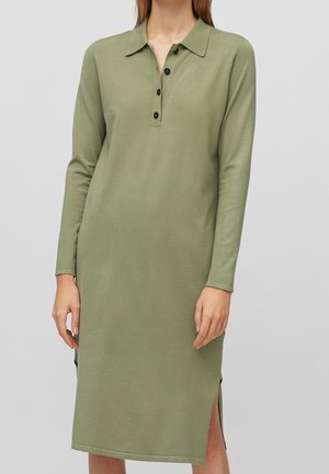 Robe à manches longues, longueur genou, en vert olive avec un col, patte de boutonnage, fentes latérales et un tissu doux et texturé.
