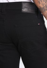 Los jeans de mezclilla negros cuentan con un bolsillo trasero cosido con un emblema, una cintura de altura media y una textura suave. Parche con logo en la cinturilla.