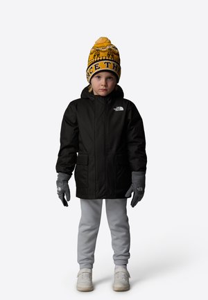 Veste isolée noire avec capuche, gants gris, jogging gris clair et un bonnet à motifs jaunes avec le texte "FACE THE" sur un enfant.