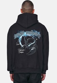 Black oversized hoodie featuring a graphic print with the text "trust nobody," a scorpion, and lightning accents on the back.
