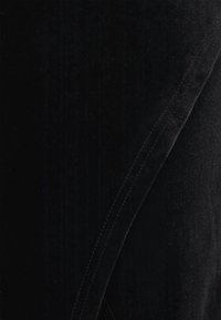 Fekete szövet sima textúrával és enyhe fényességgel. A széleken részletes varrás látható, ami tiszta, szabott megjelenést hangsúlyoz.