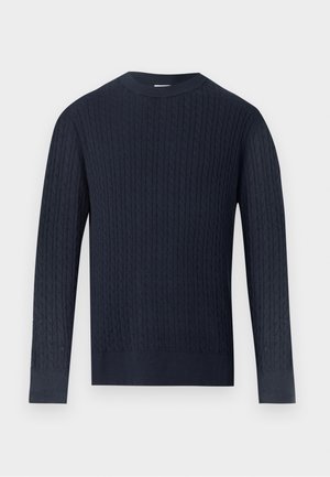 Jersey de punto tipo trenza azul marino de manga larga con cuello redondo y puños y bajo acanalados sobre un fondo gris claro.