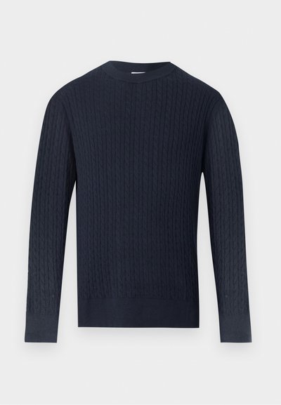 Μακρυμάνικη μπλούζα σε ναυτικό μπλε χρώμα με πλέξη καλώδιο, στρογγυλή λαιμόκοψη και ριμπ μανσέτες και τελείωμα σε γκρι ανοιχτό φόντο.