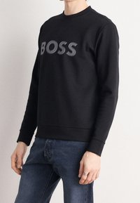 Sudadera negra de mezcla de algodón, con "BOSS" en letras grises en el pecho. Cuello redondo clásico y puños con ribete.