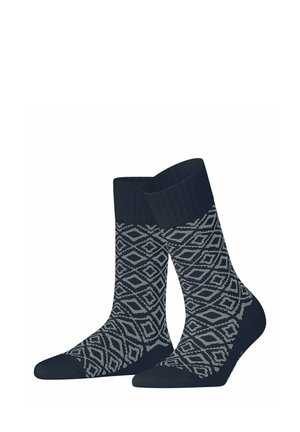 Paar schwarze Socken mit grauen geometrischen Diamantmustern und gerippten Bündchen, auf weißem Hintergrund stehend dargestellt.