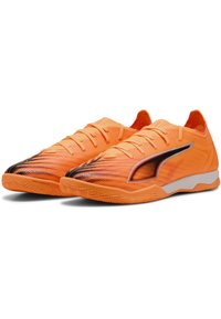 Scarpe da ginnastica arancioni vivaci con una tomaia testurizzata, dettagli neri e una suola in gomma antitraccia. Design aerodinamico con lacci.